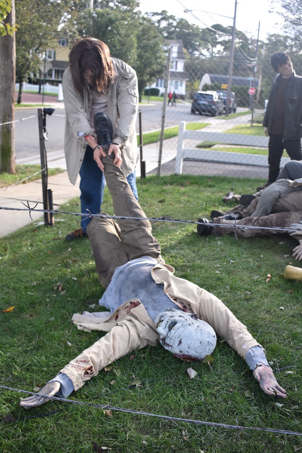 A human figure drags a zombie to a heap of other undead creatures.